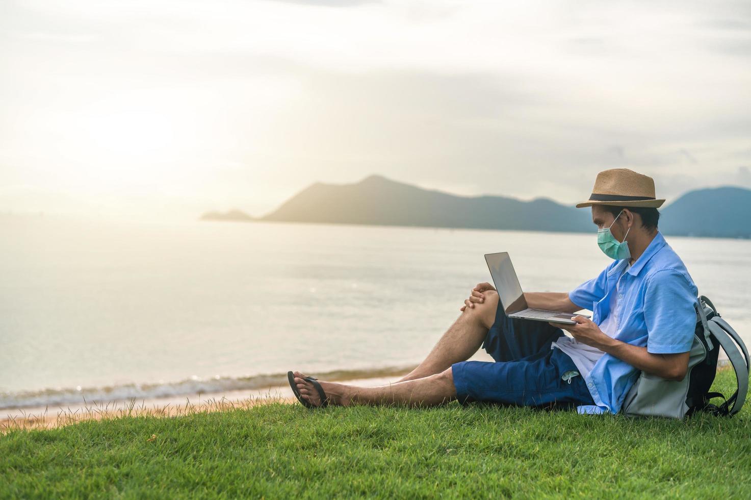 Mann trägt Maske mit Laptop-Computer am Strand Meer und Mann Reisen Urlaub Phuket Sandbox Thailand sind Freiheit Leben Finanzen foto