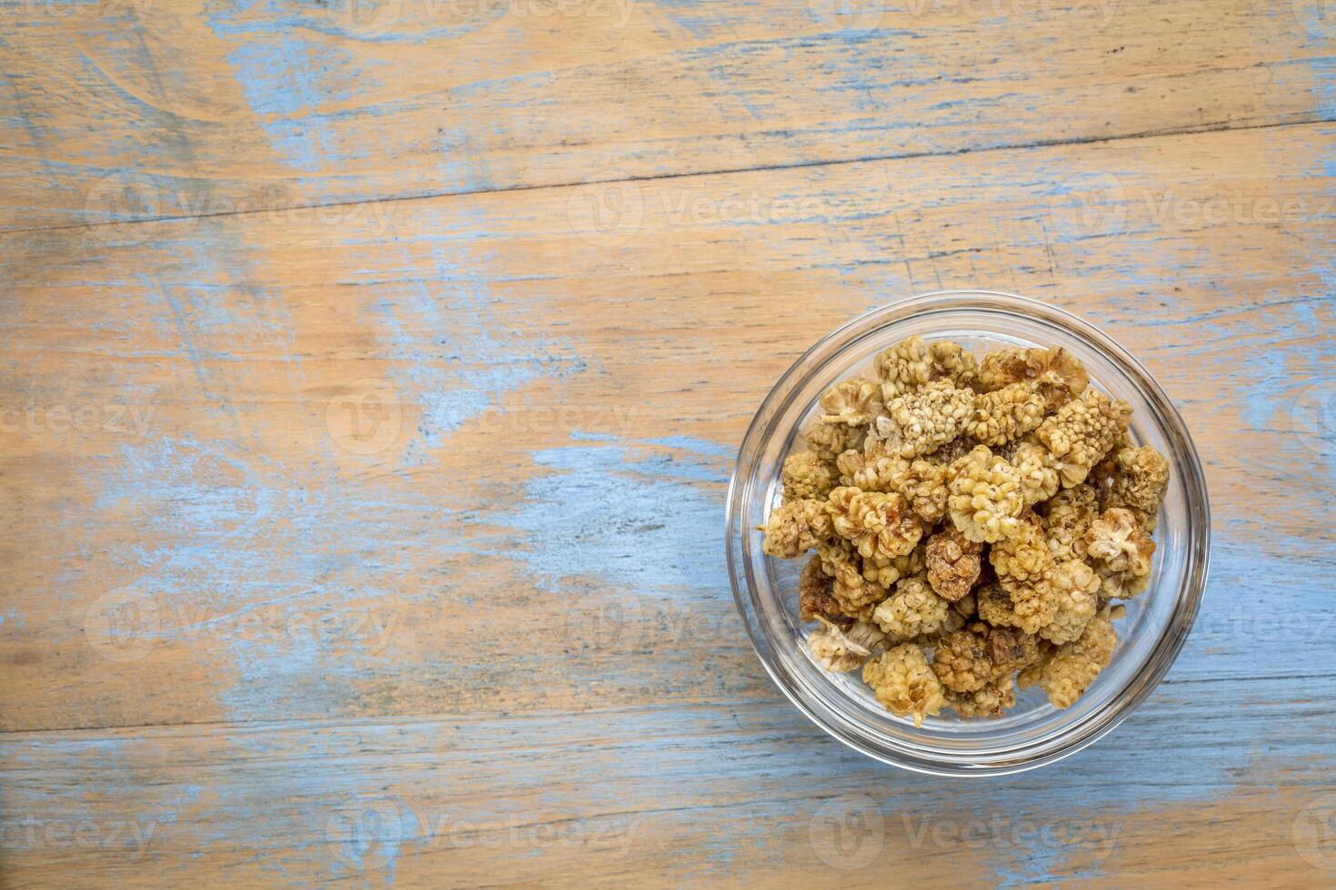 sonnengetrocknet Weiß Maulbeere Beeren im ein klein Glas Schüssel gegen Grunge Holz mit ein Kopieren Raum foto