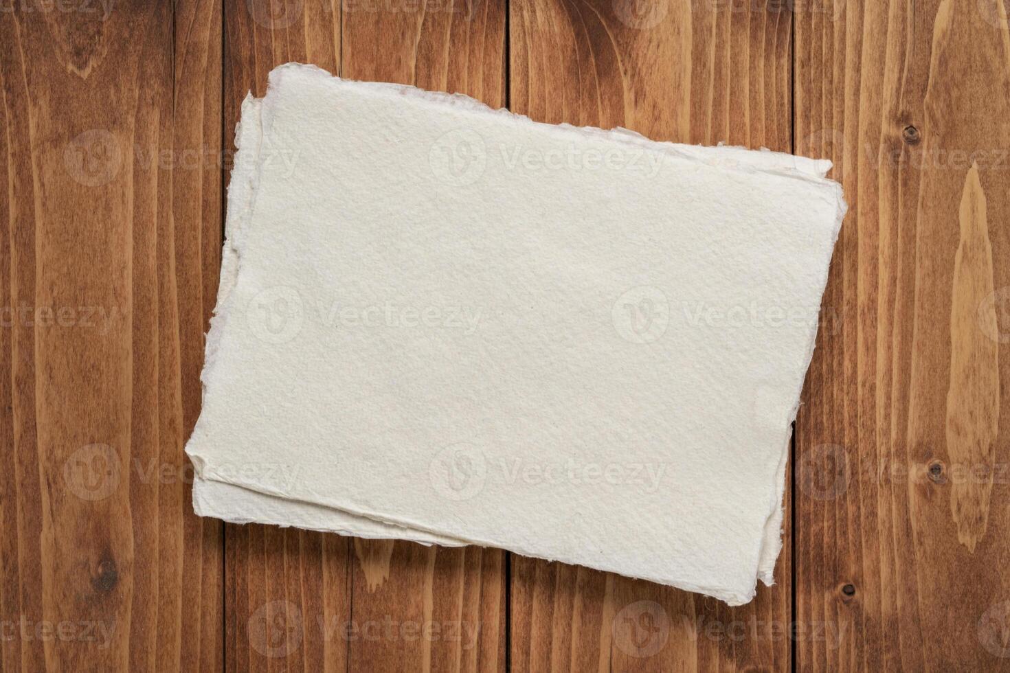klein Blatt von leer Weiß khadi Lappen Papier gegen rustikal Holz Hintergrund foto