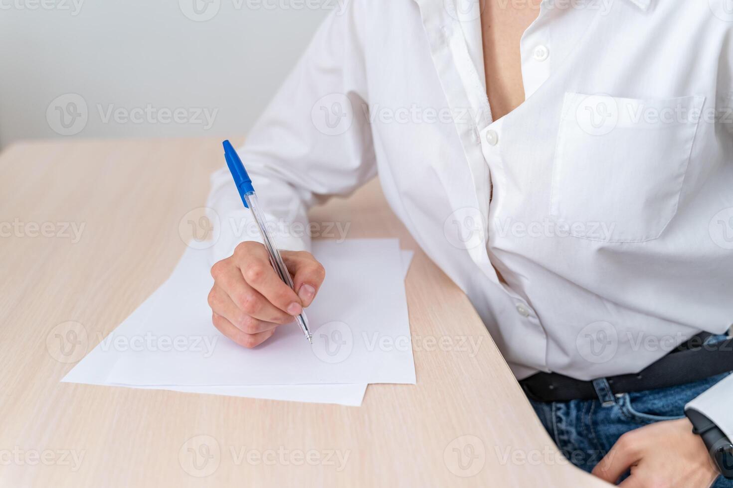 Frau beim arbeiten. Schreiben etwas Papiere auf das Schreibtisch. Zuhause Büro oder klein Unternehmen Situation mit echt Personen. weiblich ist tragen Weiß Shirt. abgeschnitten Foto. foto