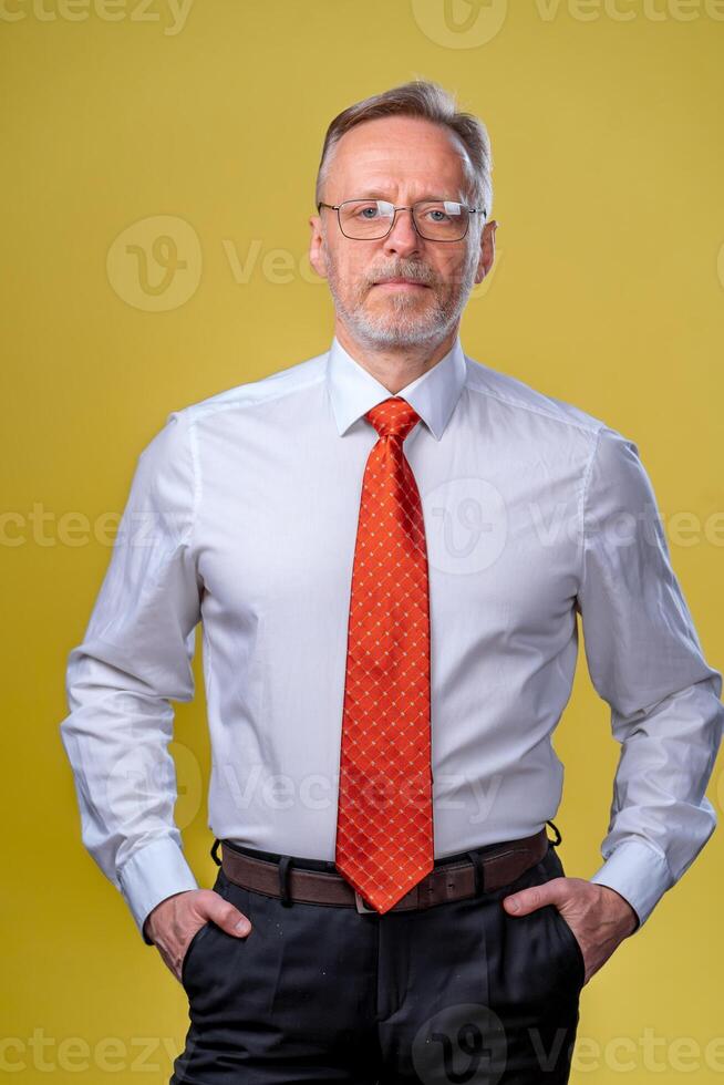 Inhalt Senior Geschäft Mann im Hemd und Weste. posieren im Studio auf Gelb Hintergrund. zuversichtlich. Geschäft Stil Konzept foto