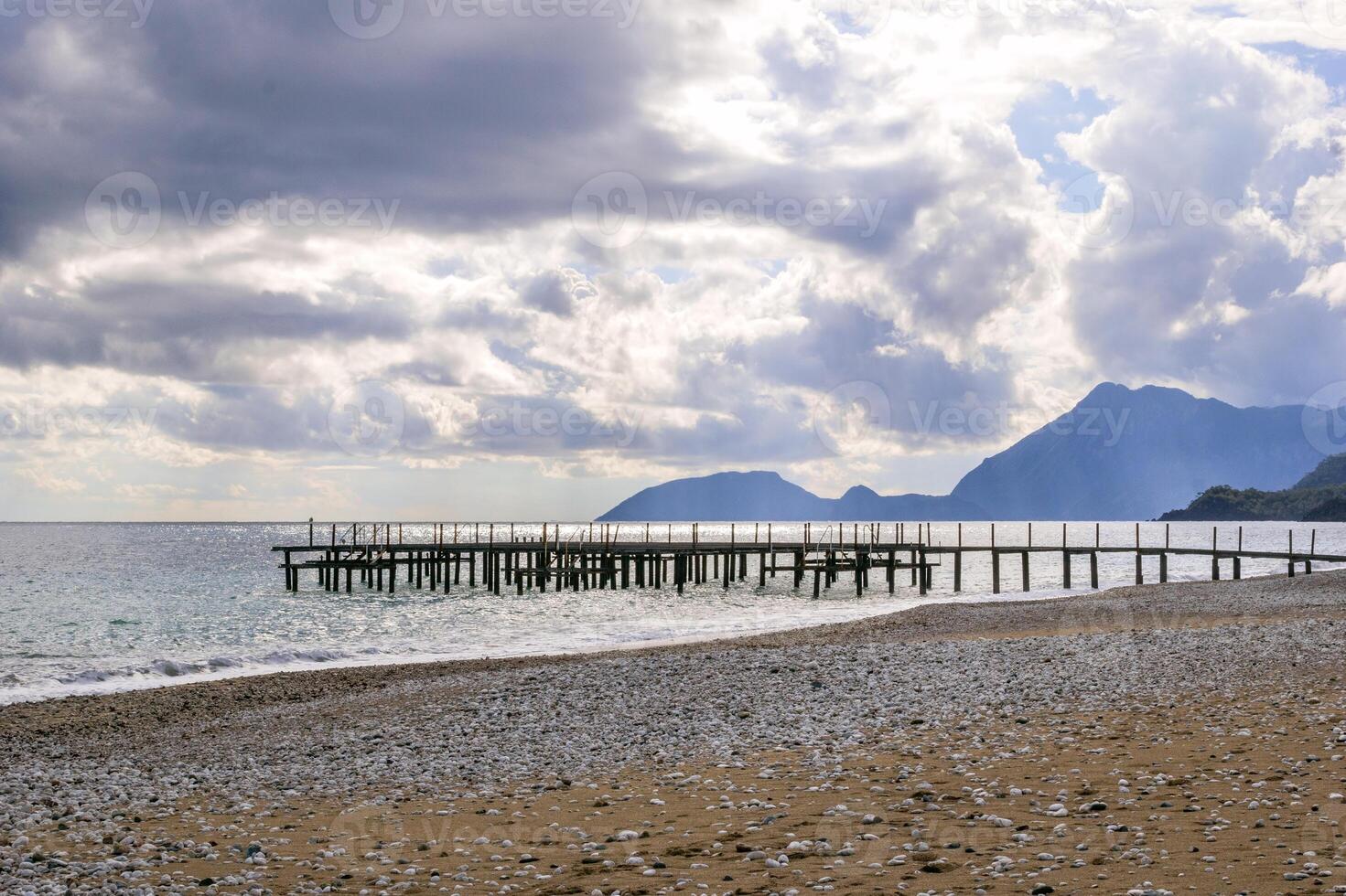 still hölzern Dock Ausdehnung in Ruhe Blau Meer mit Berg Angebot unter wolkig Himmel foto