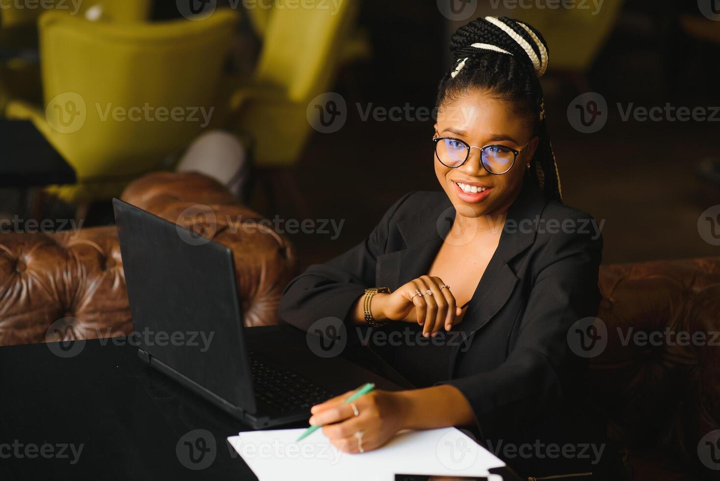 jung Mädchen im Brille erstaunlich suchen im Laptop beim Cafe. afrikanisch amerikanisch Mädchen Sitzung im Restaurant mit Laptop und Tasse auf Tisch. Porträt von überrascht Dame mit dunkel lockig Haar im Kopfhörer foto