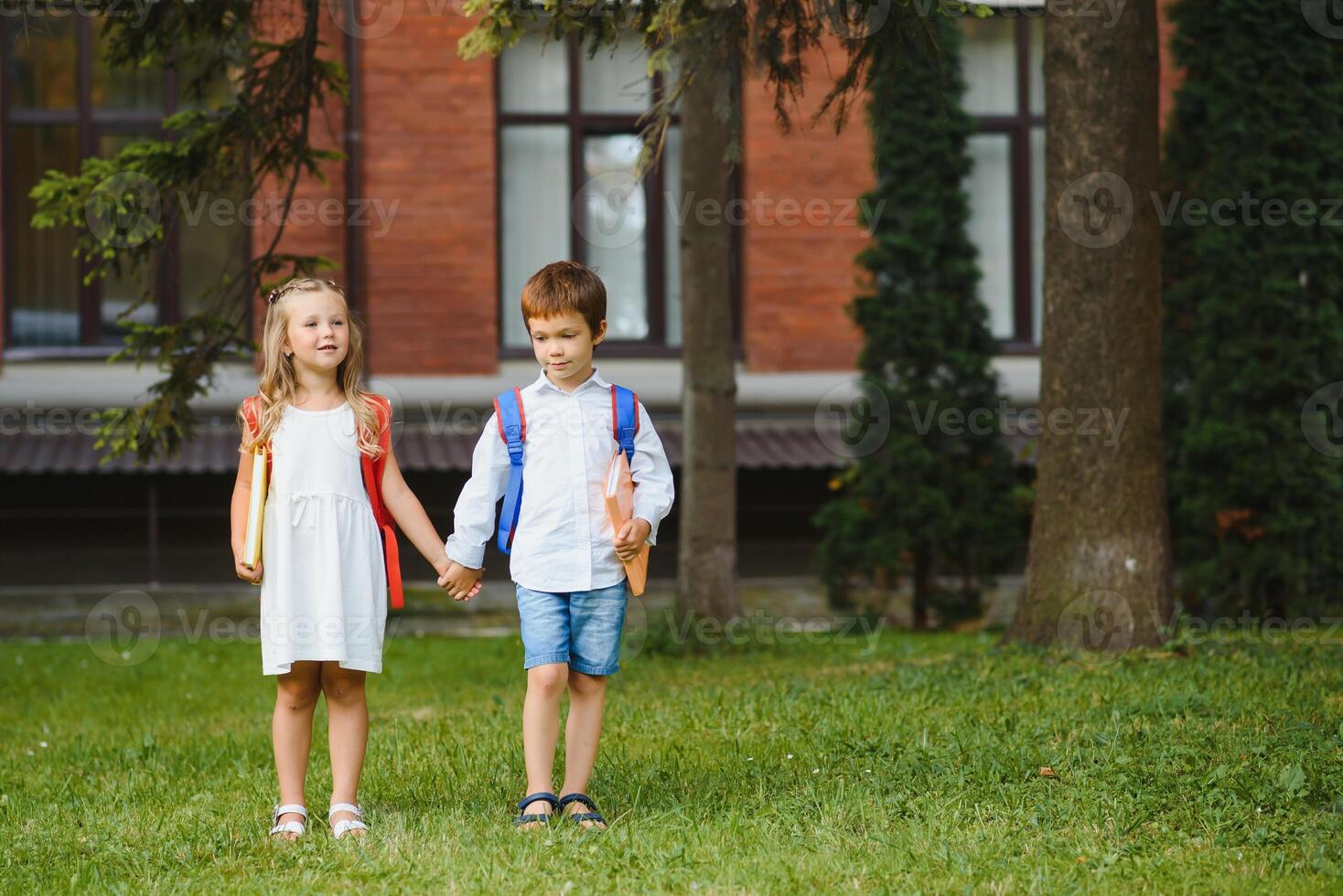 glücklich Kinder - - Junge und Mädchen mit Bücher und Rucksäcke auf das zuerst Schule Tag. aufgeregt zu Sein zurück zu Schule nach Urlaub. voll Länge draussen Porträt. foto