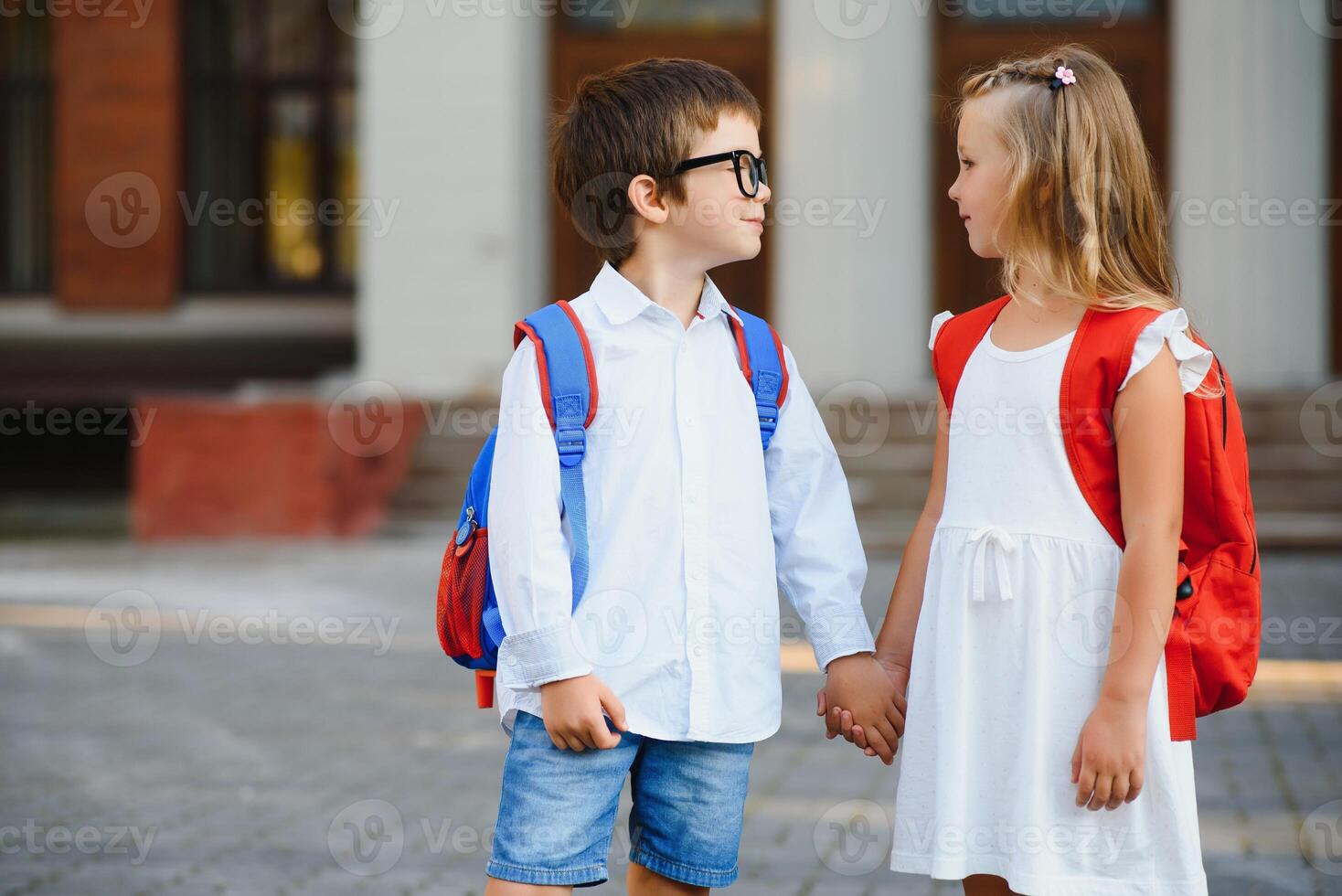 glücklich Kinder gehen zurück zu Schule. Schüler von primär Schule gehen Studie mit Rucksack draußen. Kinder gehen Hand im Hand. Anfang von Unterricht. zuerst Tag von fallen. Junge und Mädchen von elementar Student. foto