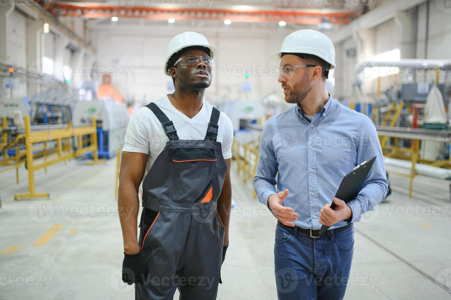 zwei vielfältig Fachmann schwer Industrie Ingenieure tragen Sicherheit Uniform und schwer Hüte Arbeiten auf Laptop foto