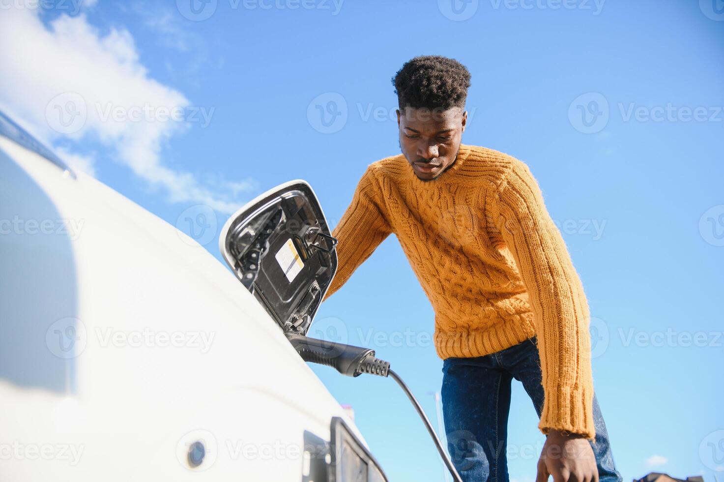 afrikanisch amerikanisch Mann Laden seine elektrisch Wagen. foto