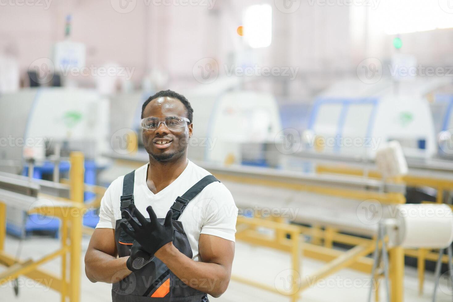 Porträt von afrikanisch amerikanisch männlich Ingenieur im Uniform und Stehen im industriell Fabrik foto