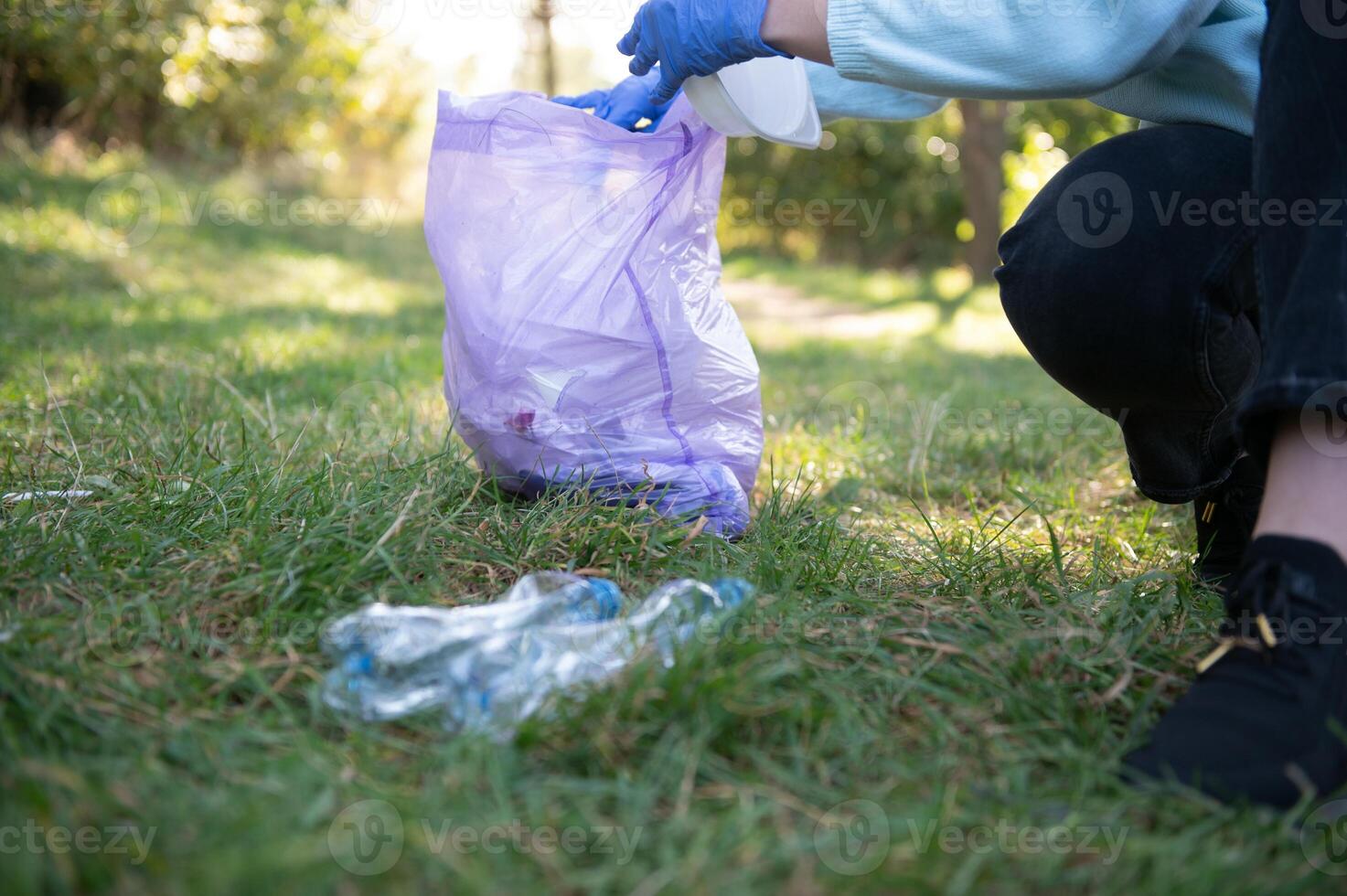 Hand setzt Plastik Trümmer im das Müll Tasche im das Park foto