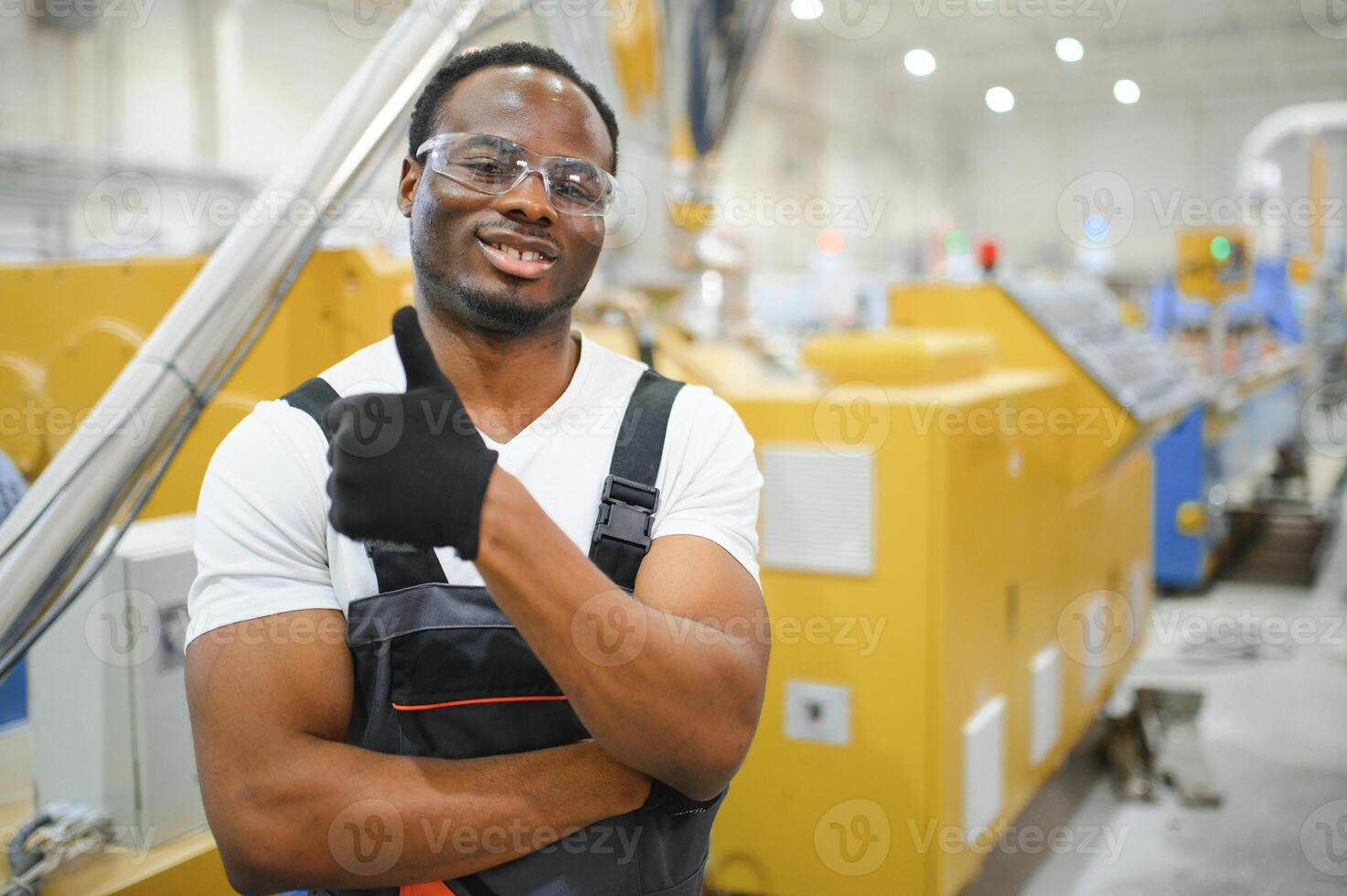 Porträt von afrikanisch amerikanisch männlich Ingenieur im Uniform und Stehen im industriell Fabrik foto