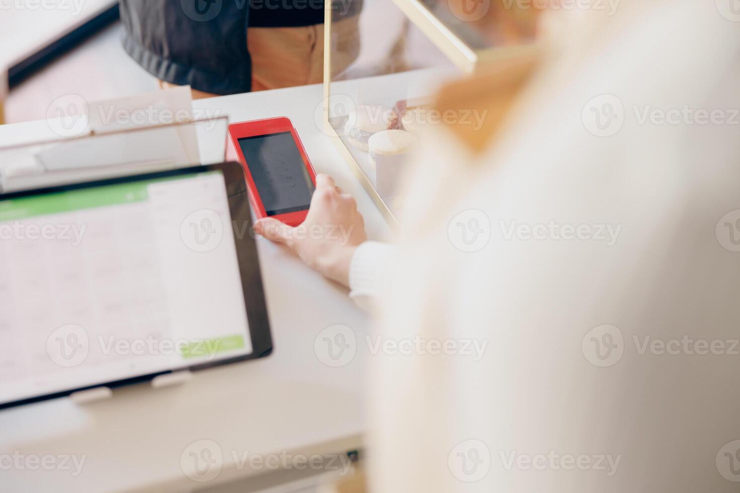 schließen oben von Barista hält aus ein Terminal zum kontaktlos bezahlen zu ein Klient im Kaffee Geschäft foto