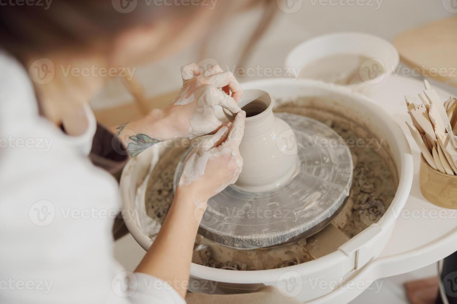 weiblich Töpfer im Schürze Herstellung gestalten von Lehm Vase auf Spinnen Keramik Werkzeug im Keramik Werkstatt foto