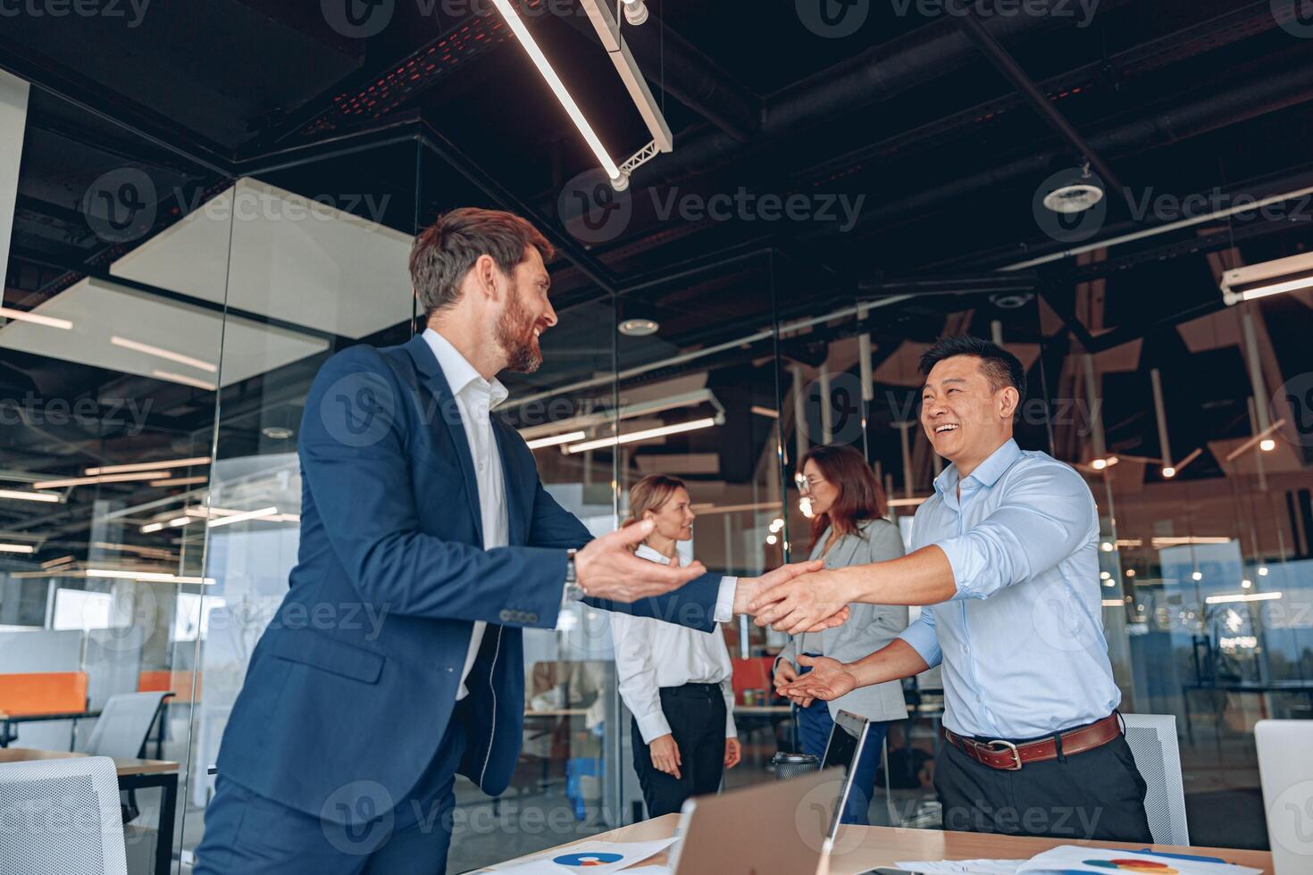 Kollegen sind zittern ihr Hände im modern Büro während Zusammenarbeit Treffen foto