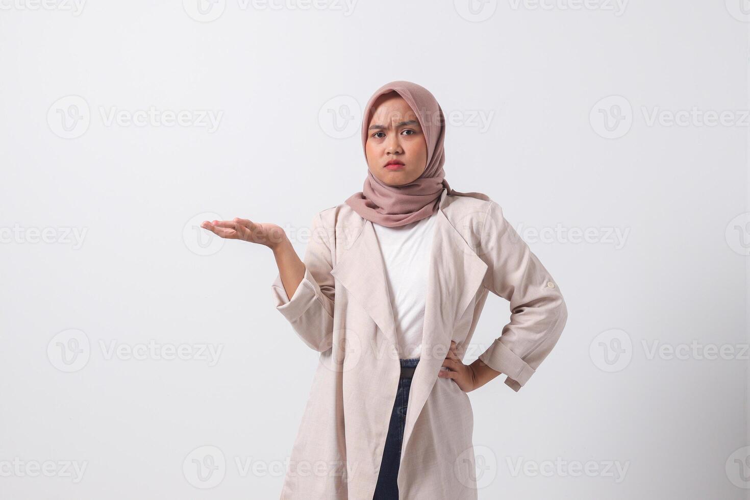Porträt von verwirrt asiatisch Hijab Frau im beiläufig passen Verbreitung Hände seitwärts, Gefühl Zweifel während Herstellung Auswahl. Geschäftsfrau Konzept. isoliert Bild auf Weiß Hintergrund foto