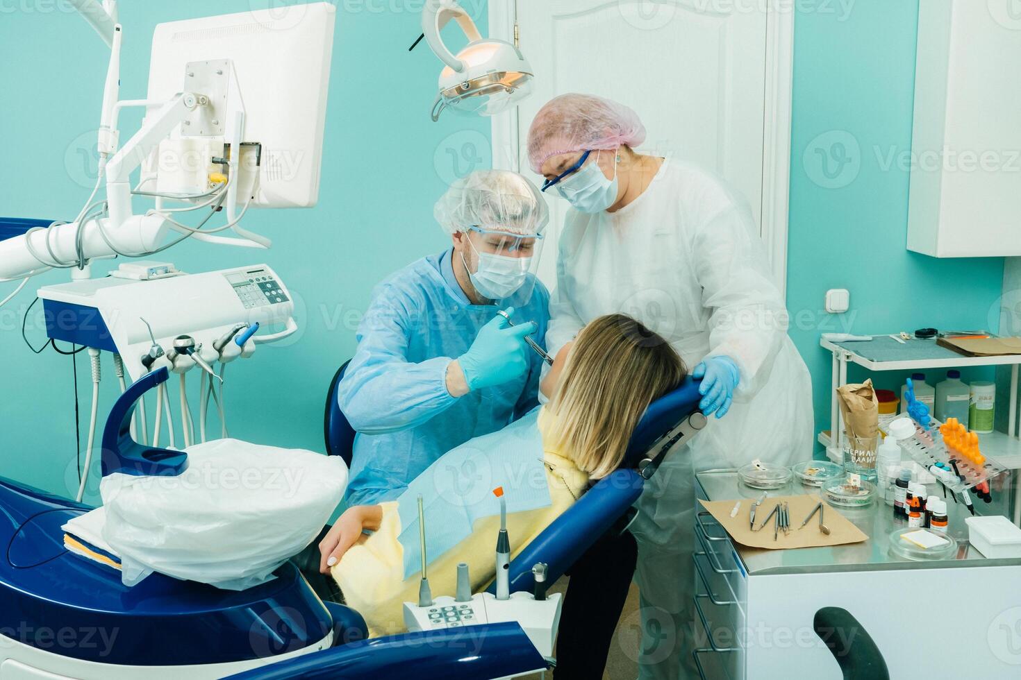 ein Zahnarzt im ein schützend Maske Kolitis Schmerzmittel im das Dental Büro mit ein Assistent foto