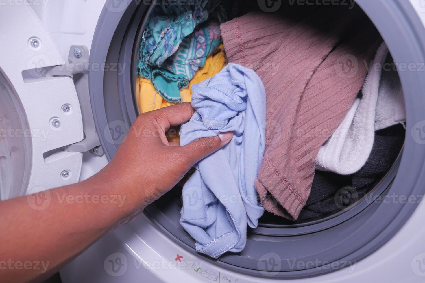 Mann steckt Hemd in die Waschmaschine. foto