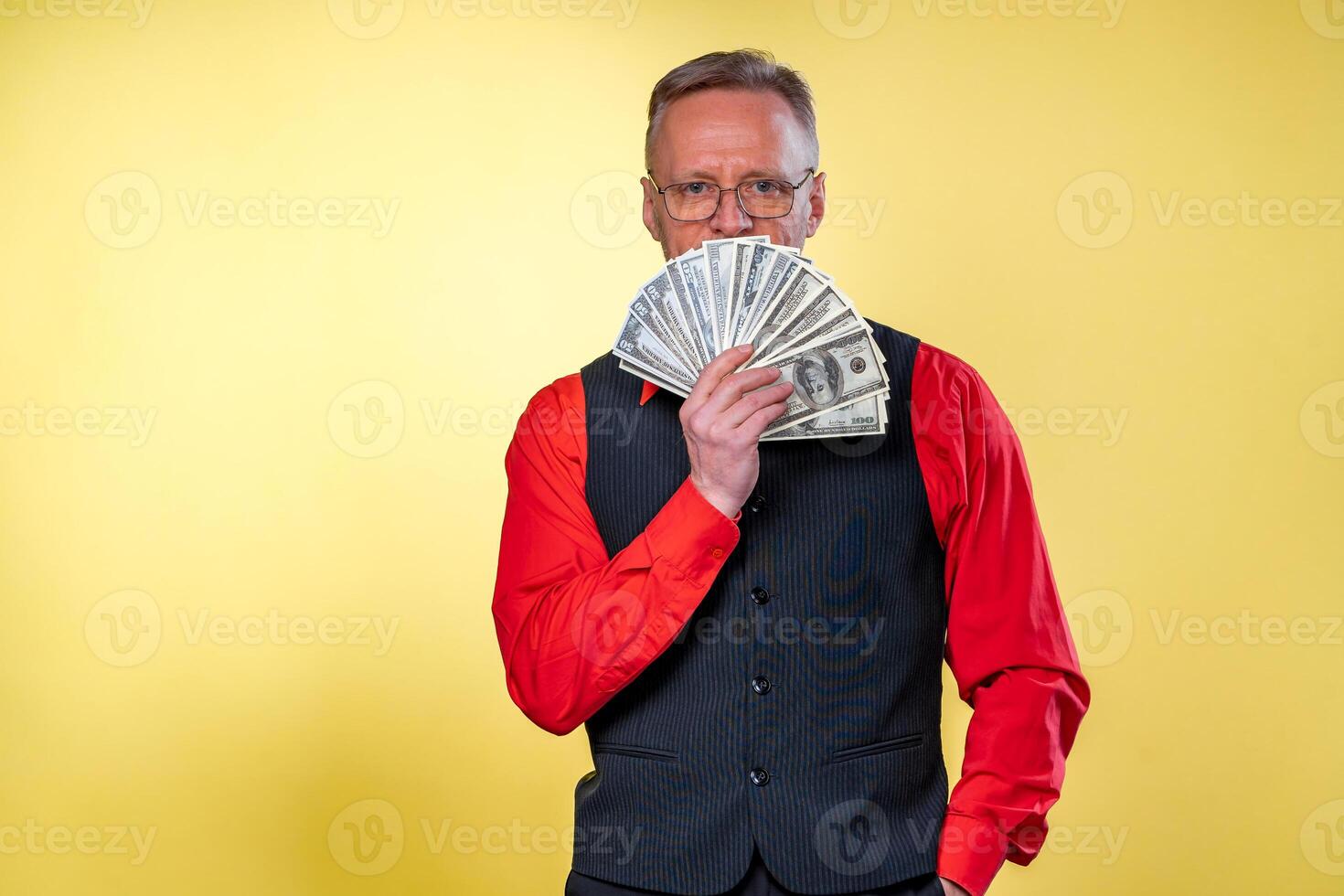 alt lächelnd grauhaarig Mann im Brille. Mann halten Ventilator von Dollar in der Nähe von Gesicht. Mensch Emotionen und Gesichts- Ausdrücke foto