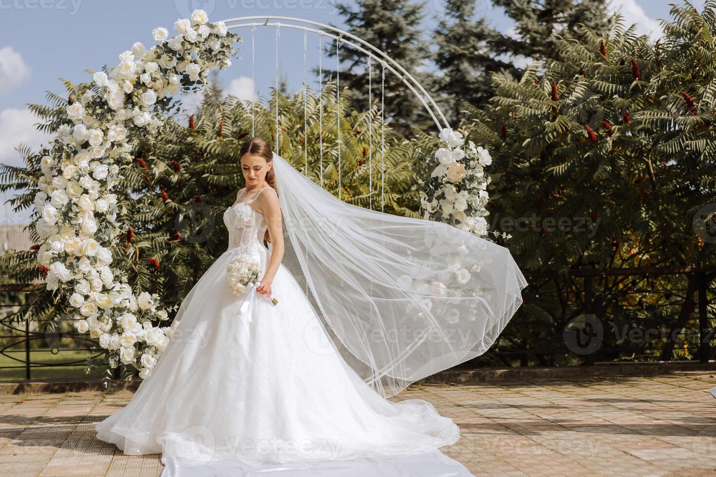 ein schön Braut im ein üppig Weiß Hochzeit Kleid gegen das Hintergrund von ein zeremoniell Bogen. foto