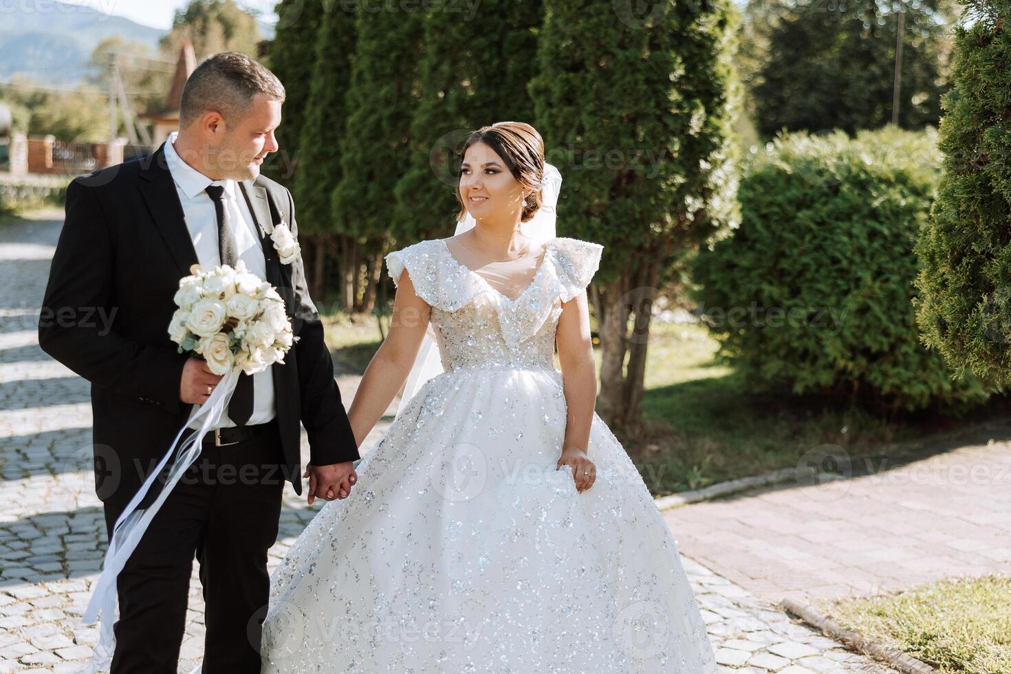 ein Hochzeit Paar ist Gehen im Natur auf ein Herbst Tag. glücklich jung Braut und elegant Bräutigam halten Hände. ein stilvoll Paar von Jungvermählten auf ihr Hochzeit Tag. foto