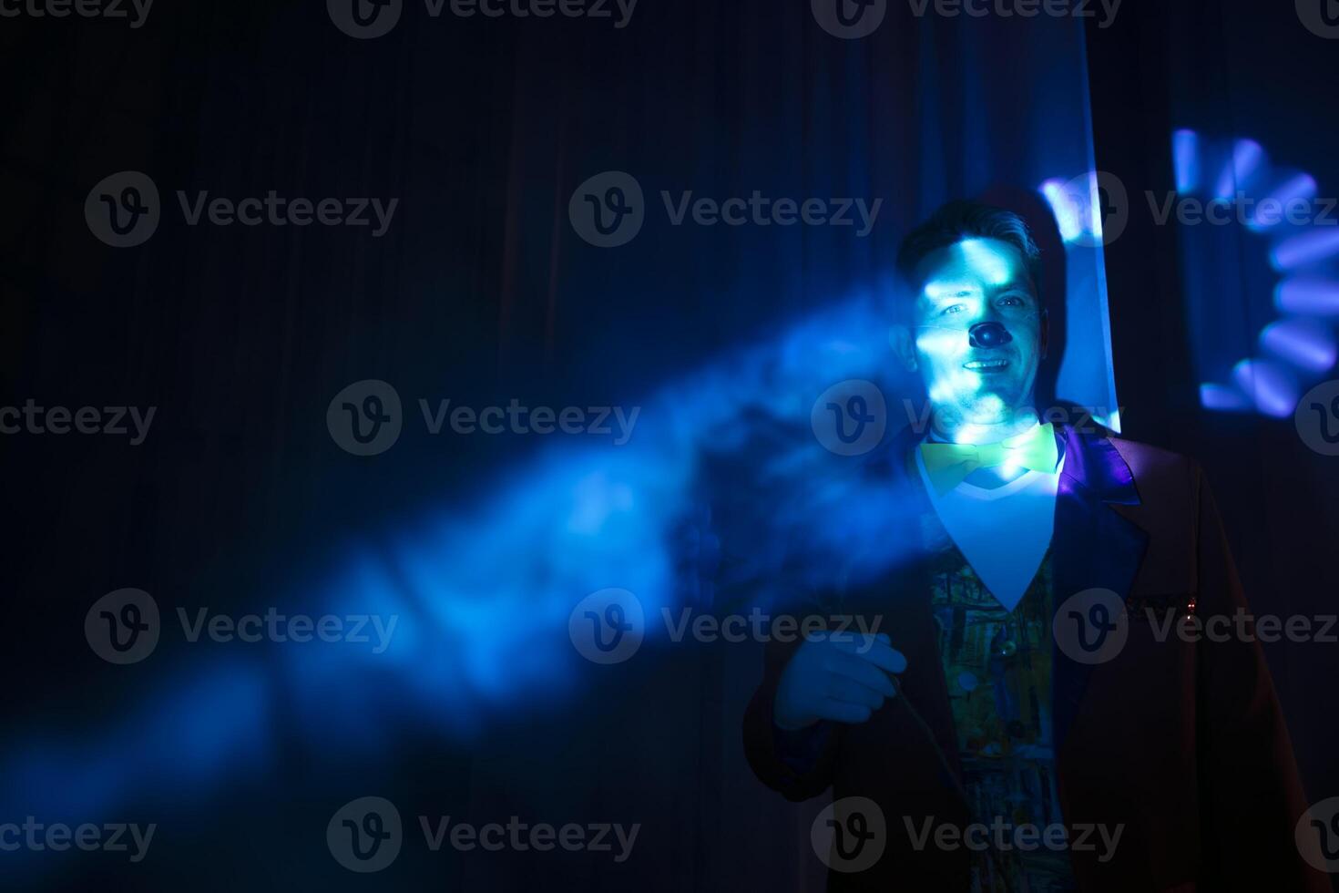 das Clowns Gesicht im ein Strahl von Bühne Blau Licht. foto