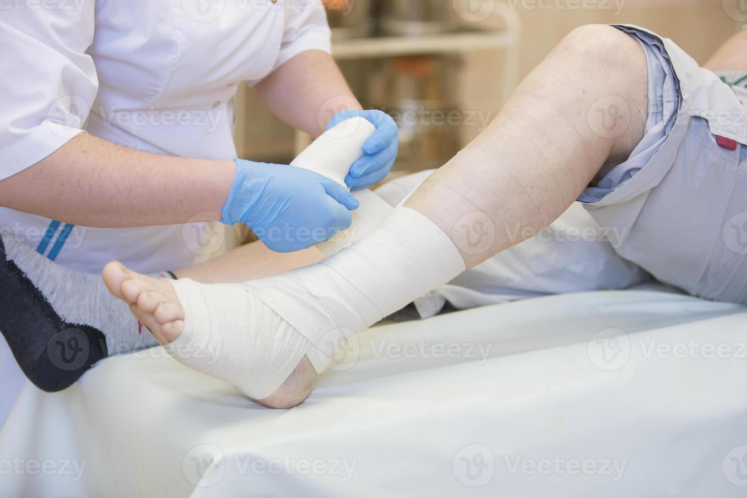 Krankenschwester Bandagen das Bein. Fraktur von Mensch niedriger Glieder. Behandlung von gebrochen Knochen. auferlegen ein Gips. geduldig chirurgisch Abteilung. das Arzt Hände spannen das Binde auf seine Bein foto