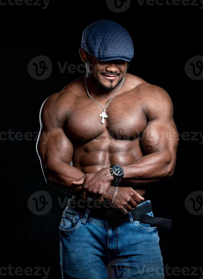 Porträt von ein stark Afroamerikaner Mann zeigen aus seine Körperbau gegen zurück Hintergrund. Mann mit perfekt Körper posieren beim das Studio foto