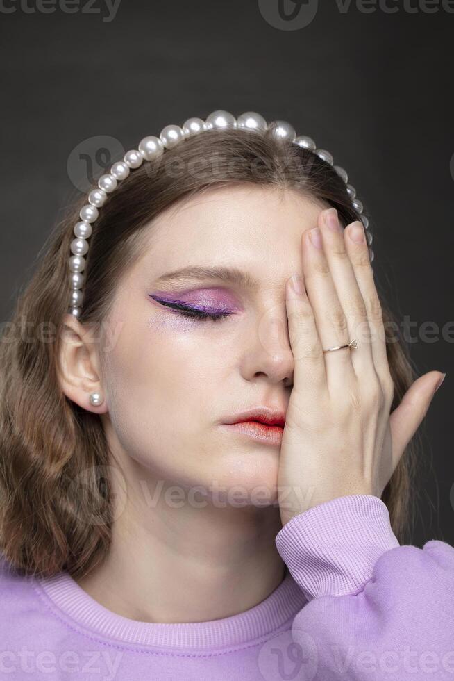 schön Mädchen Modell- bedeckt Hälfte von ihr Gesicht mit ihr Hand. foto