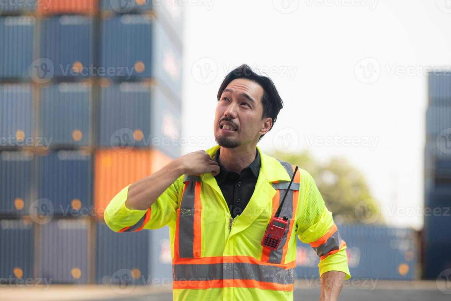 Porträt von ein asiatisch männlich Arbeiter tragen ein Sicherheit Weste und schwer Hut, nehmen ein brechen von Arbeit mit ein Container Box im das Hintergrund foto