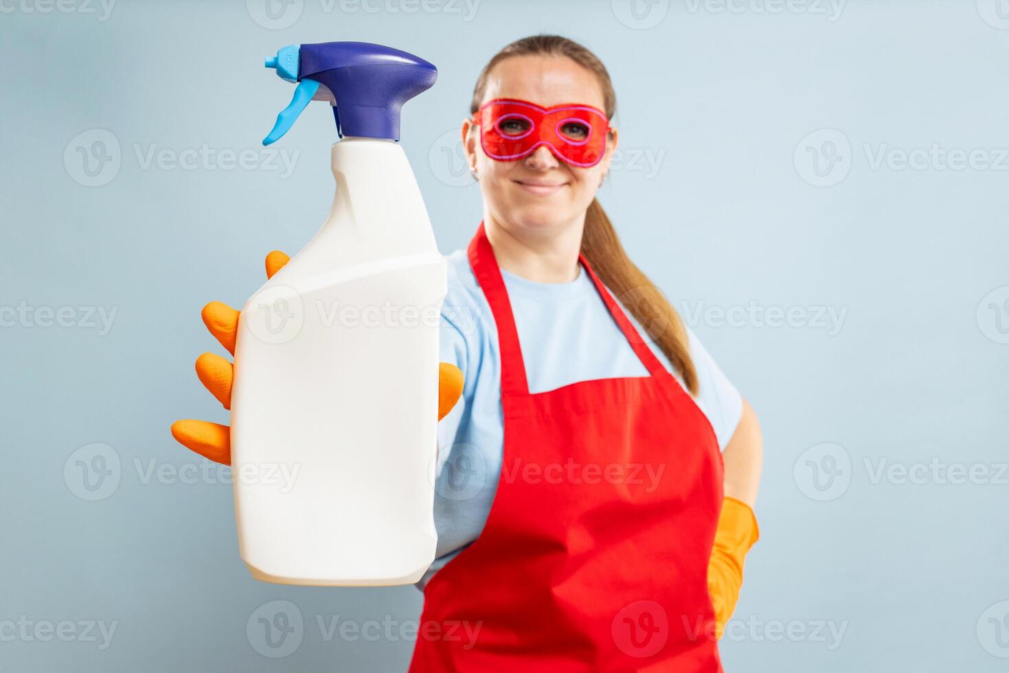 Frau im rot Maske, Gummi Handschuhe und Schürze halten Reinigung Agent Flasche foto