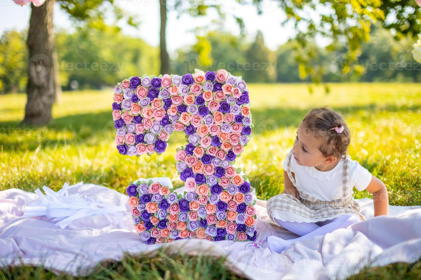 heiter Mädchen haben Spaß auf Kind Geburtstag auf Decke mit Papier Dekorationen im das Park foto