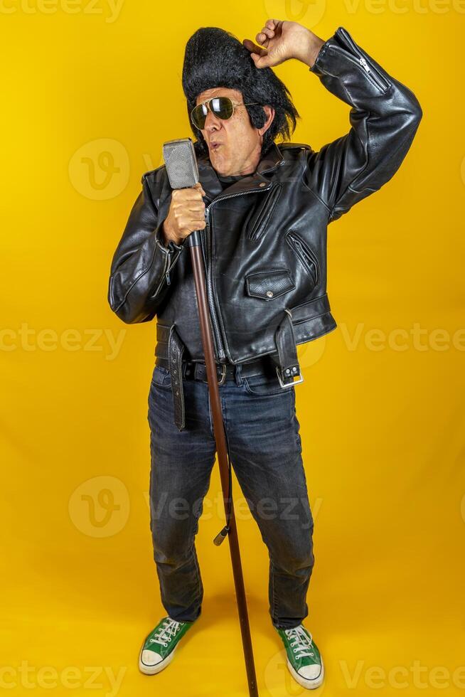komisch Porträt von reifen Rocker. ein alt Sänger gekleidet im Rockabilly Stil im Aktion foto