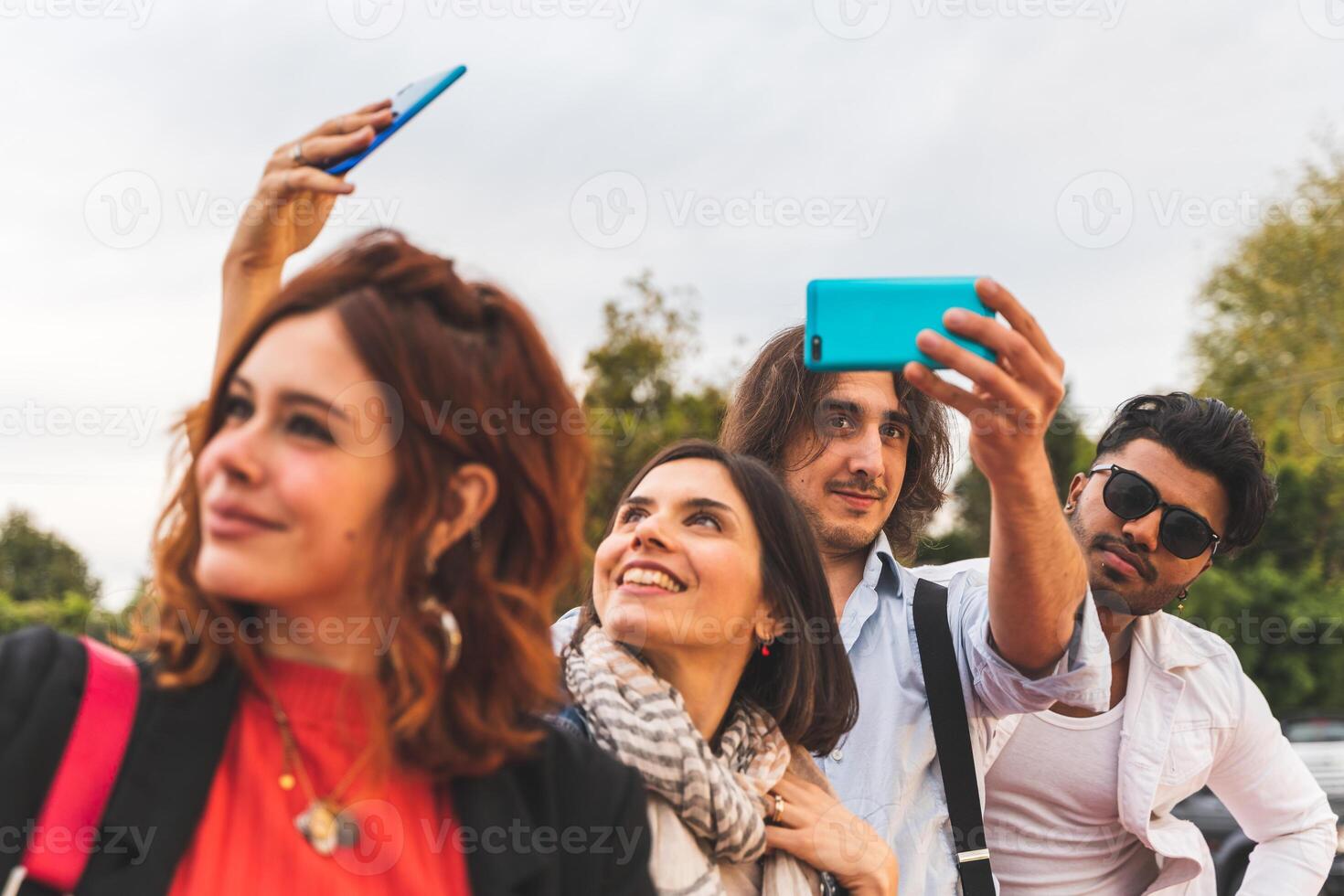 Gruppe von multikulturell Beste freunde nehmen ein Selfie mit Clever Telefone draußen foto