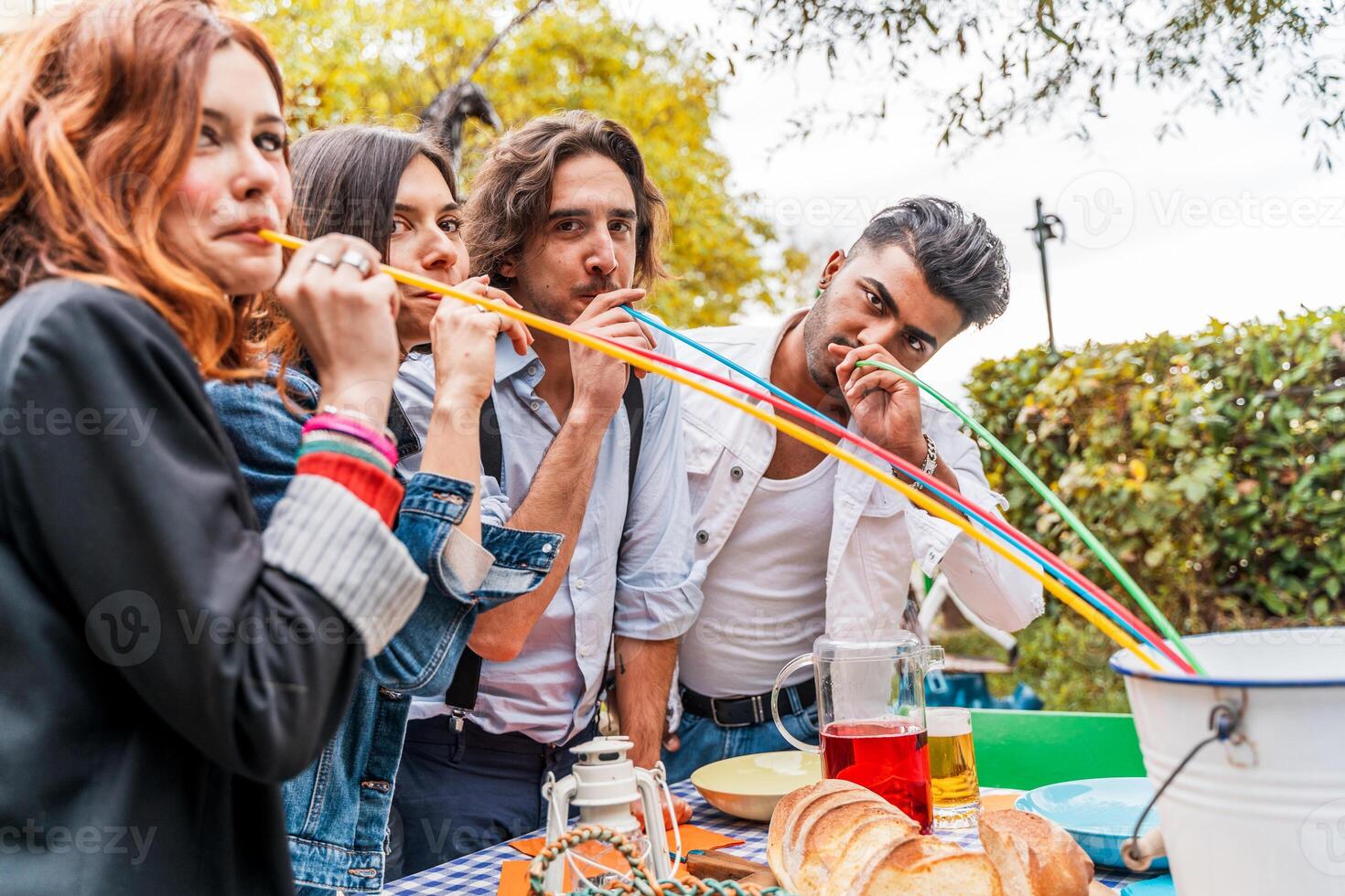 Gruppe von multikulturell freunde haben Spaß beim das Garten Party saugen Bier von bunt Strohhalme foto