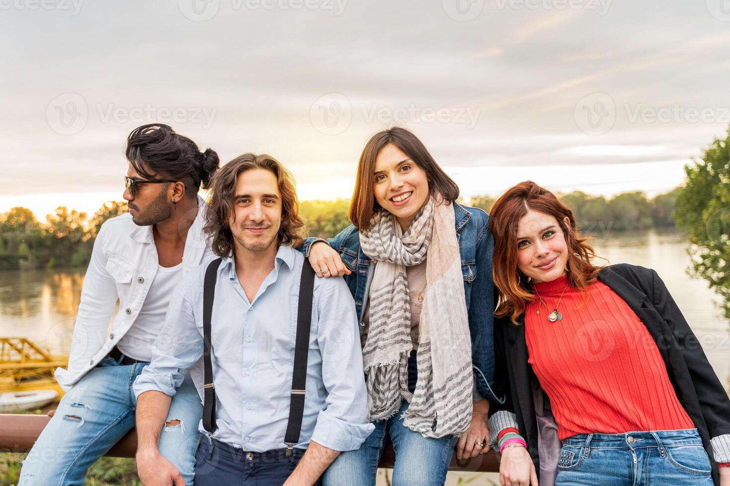 Gruppe von Beste Freund haben Spaß im Vorderseite von ein groß Fluss im Herbst beim Sonnenuntergang foto