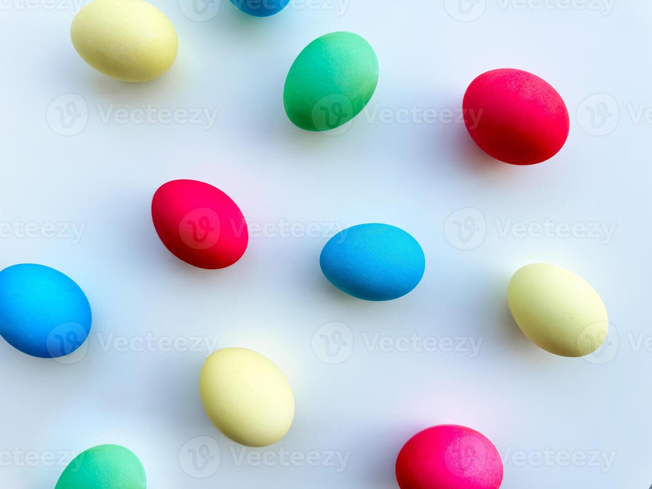 bunt Ostern Eier verstreut auf Weiß Hintergrund, eben legen Komposition zum Frühling Urlaub Feier und Dekoration Ideen. zum Ostern Urlaub Werbeaktionen, thematisch Party Einladungen, saisonal foto