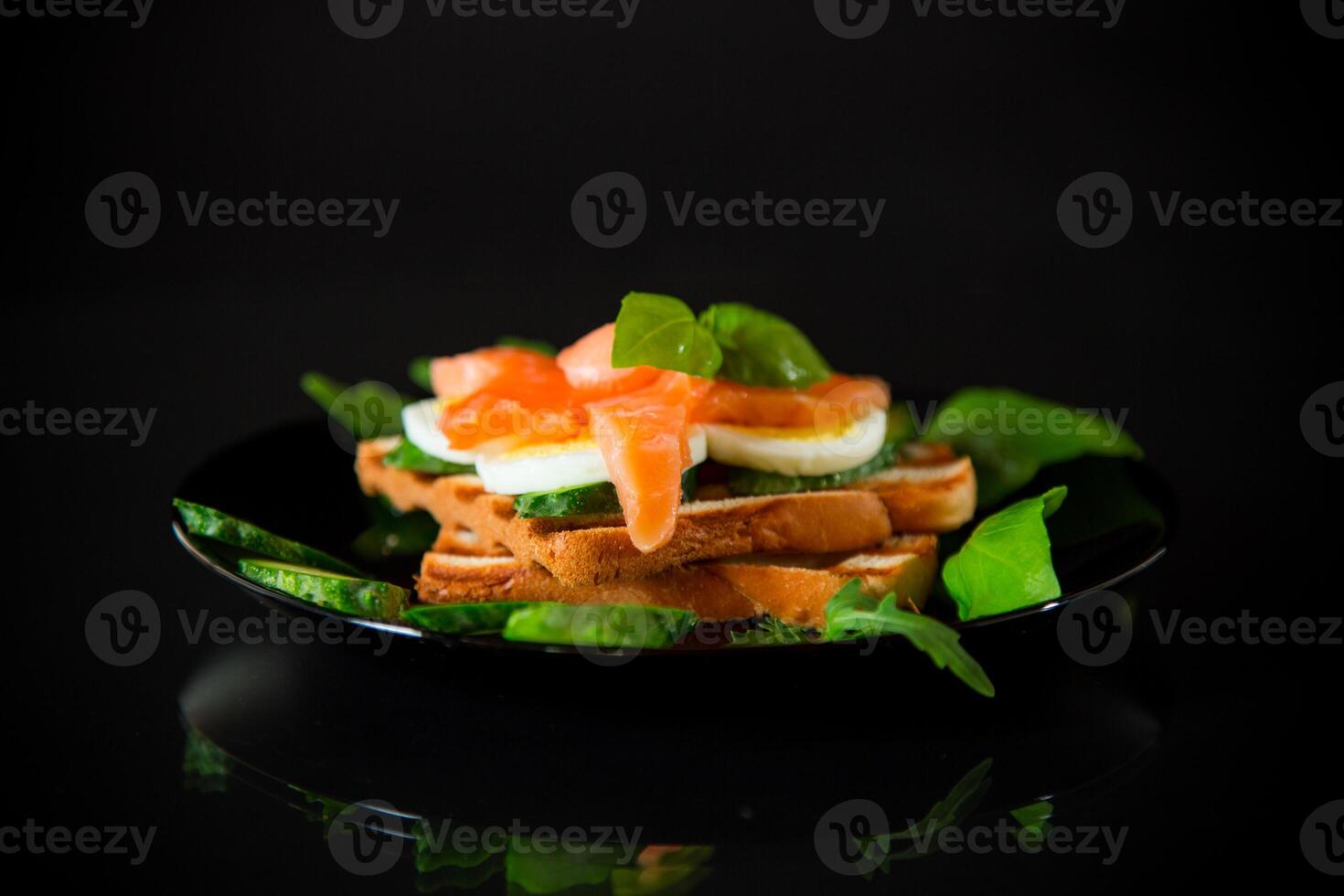 gekocht Sandwich mit leicht gesalzen rot Fisch, Gurken und gekocht Eier mit Kräuter. foto