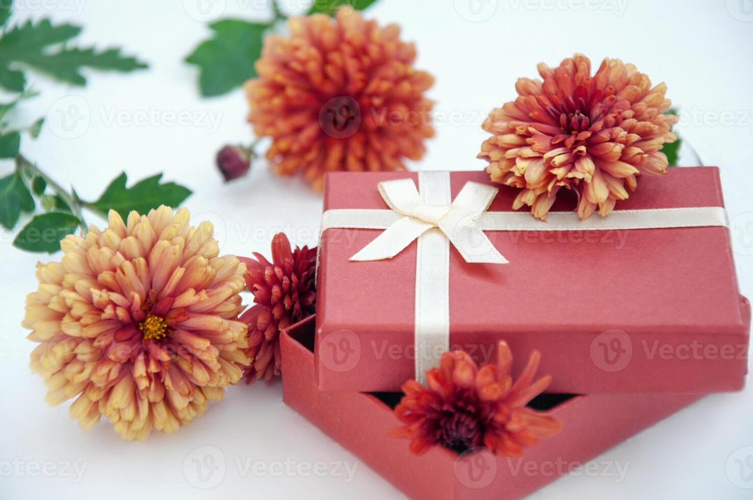 rot Geschenk Box mit Orange Chrysanthemen auf Weiß Hintergrund foto