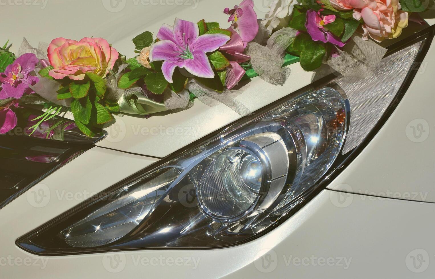 ein detailreiches Foto der Motorhaube des Hochzeitsautos, geschmückt mit vielen verschiedenen Blumen. Das Auto wird für eine Hochzeitszeremonie vorbereitet