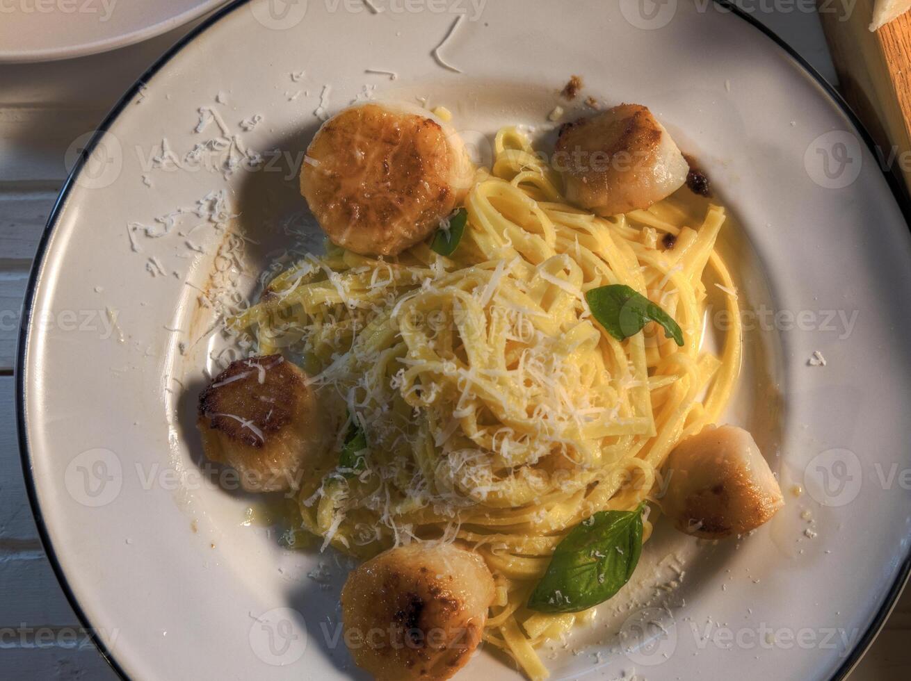 oben Aussicht Jakobsmuscheln und Pasta Gericht auf natürlich Holz Oberfläche foto