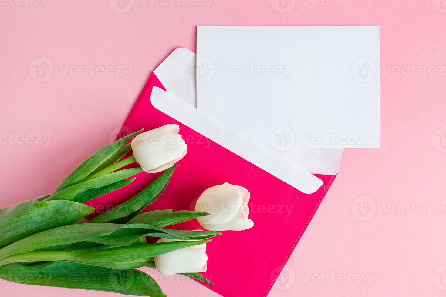 umschlag mit einladung zum urlaub und blumenstrauß aus tulpen auf rosa hintergrund. foto