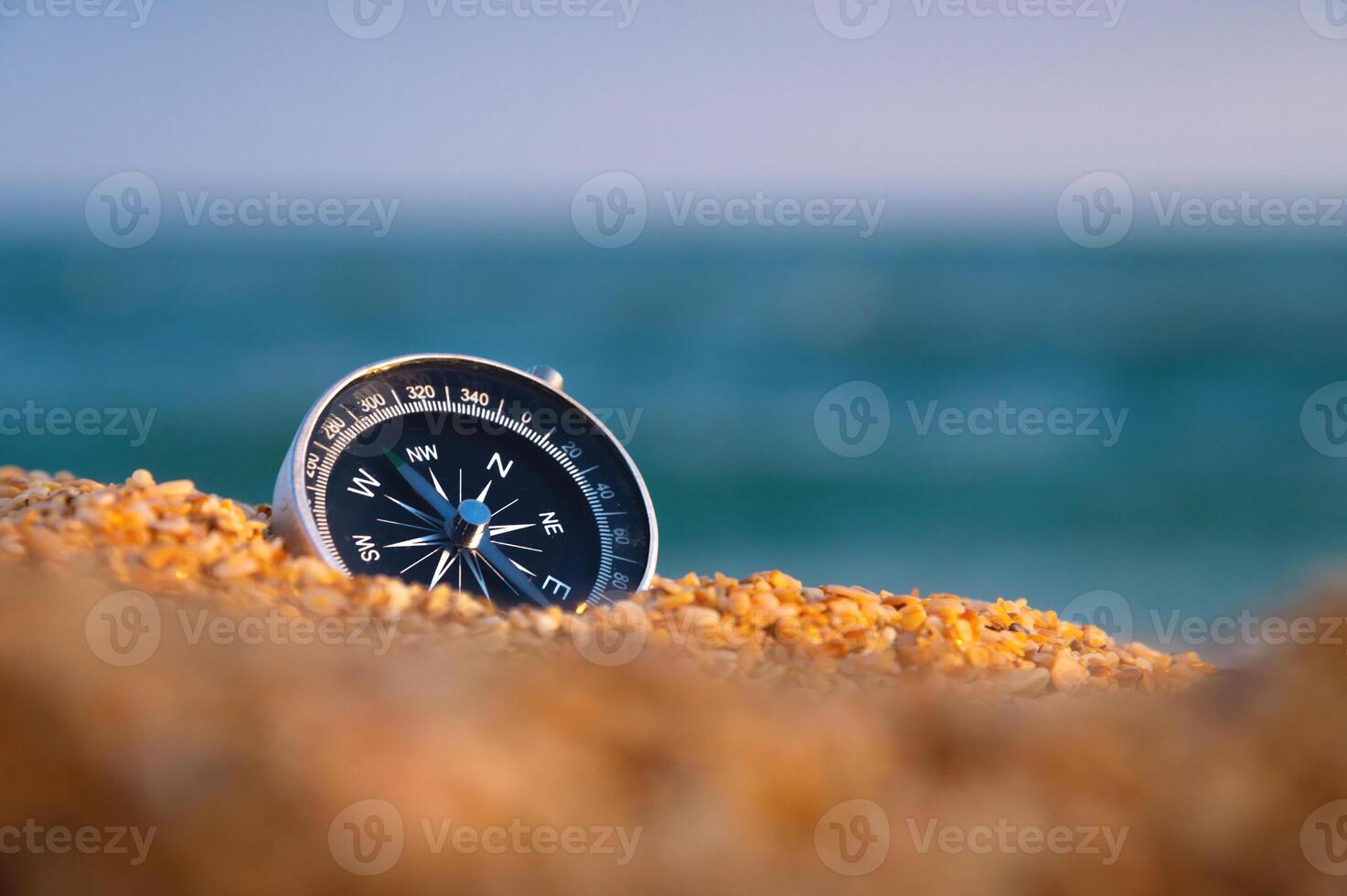 konzeptionelle Foto von ein Kompass im grob Sand gegen das Hintergrund von das Meer und Himmel, Nahaufnahme, ohne Menschen