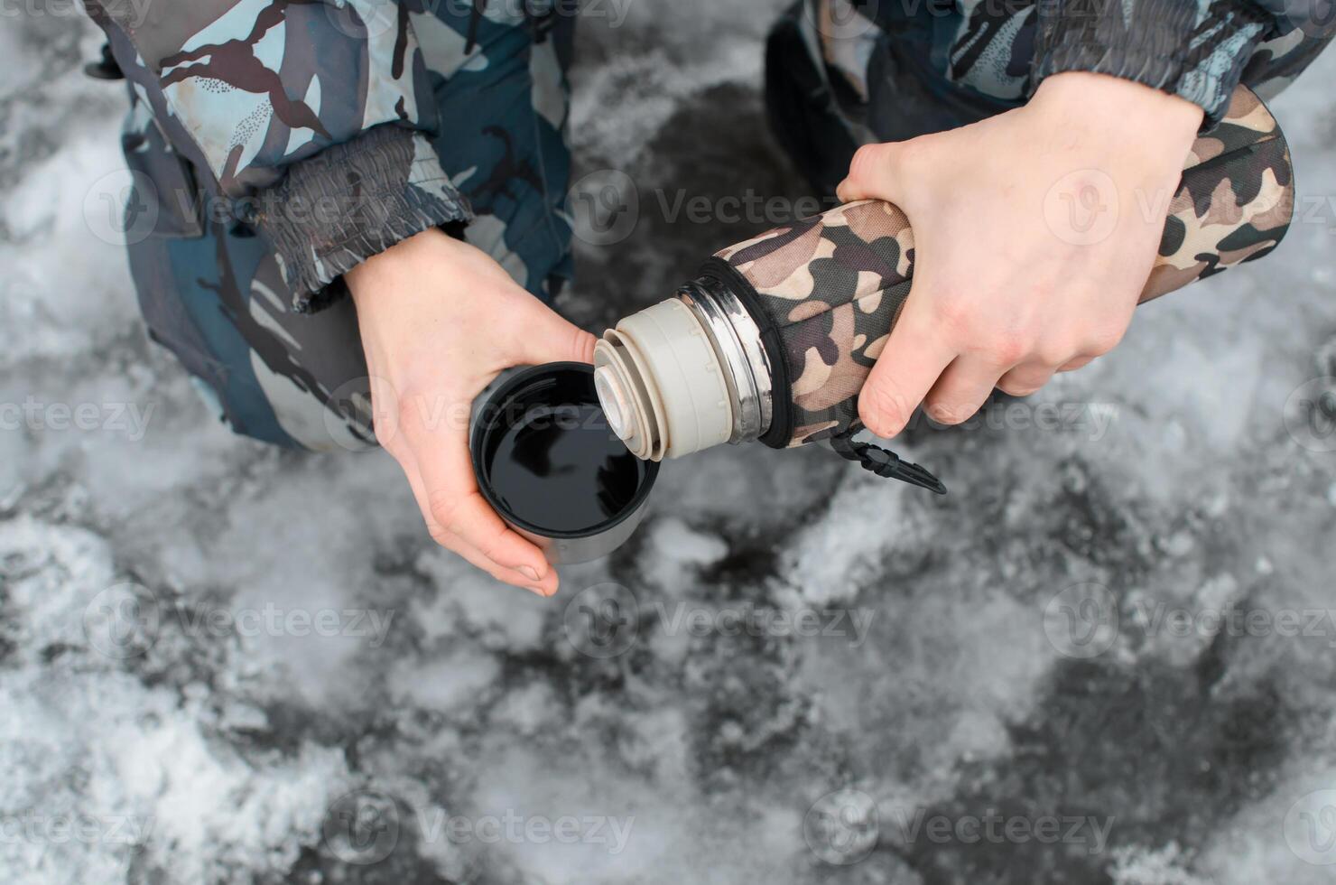 Mann gießt ein heiß trinken draußen im Winter. männlich Hände halten Thermosflasche und Becher, oben Aussicht Nahansicht foto