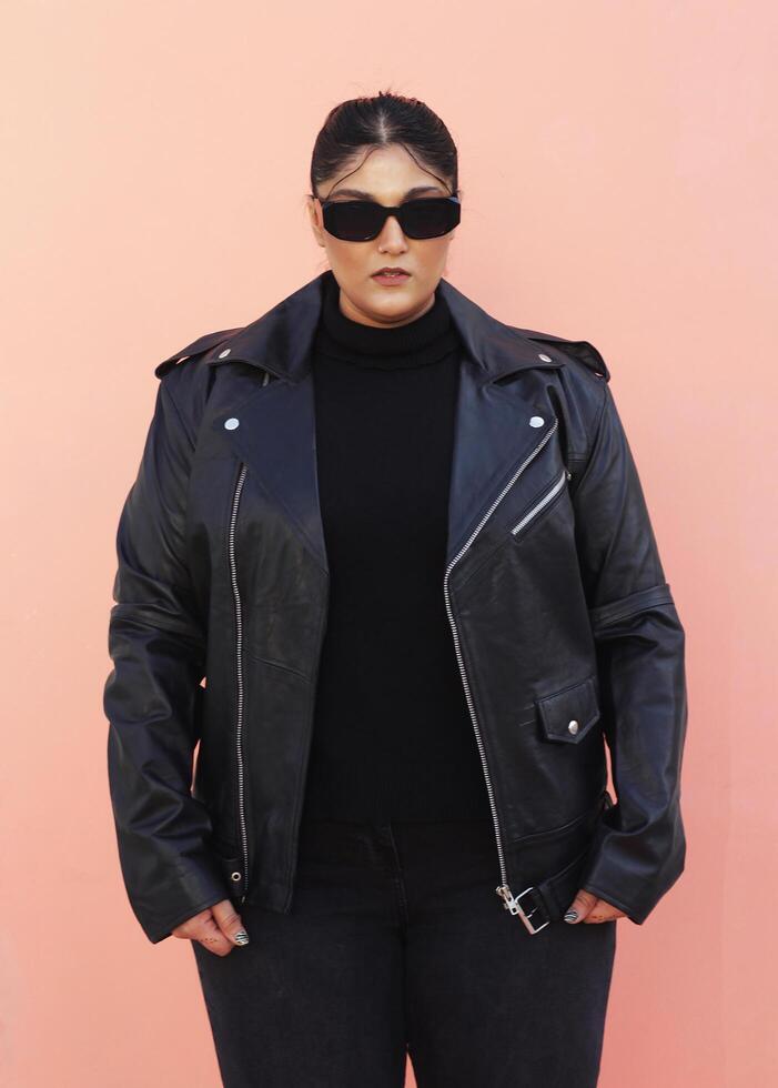 ein Frau im ein schwarz Leder Jacke und Jeans posieren zum Bild mit Brille foto
