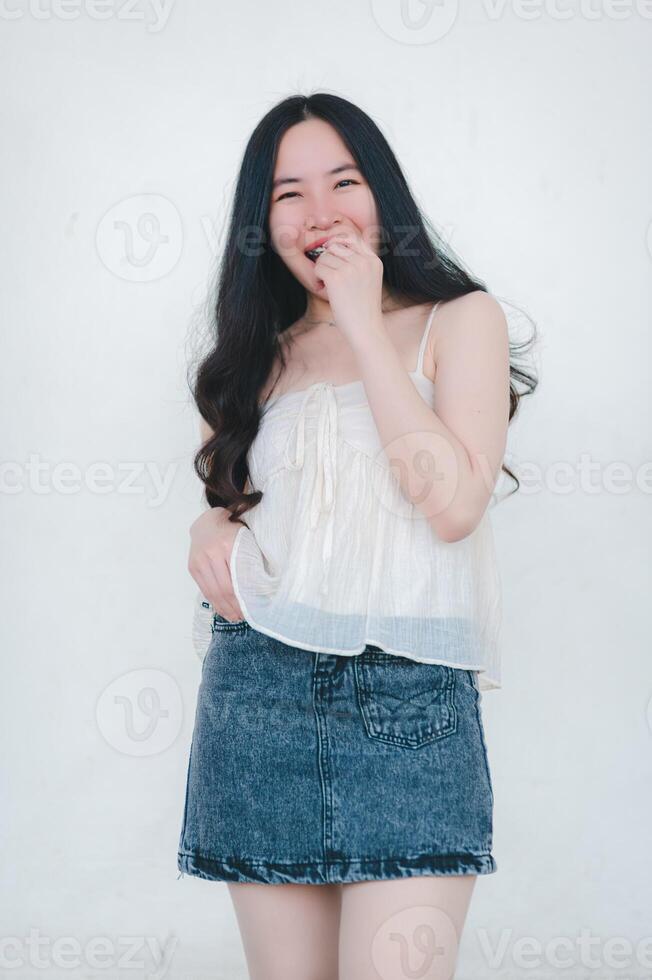 schön asiatisch Frau posiert im Mode Stil, Weiß Shirt, Jeans Rock. foto