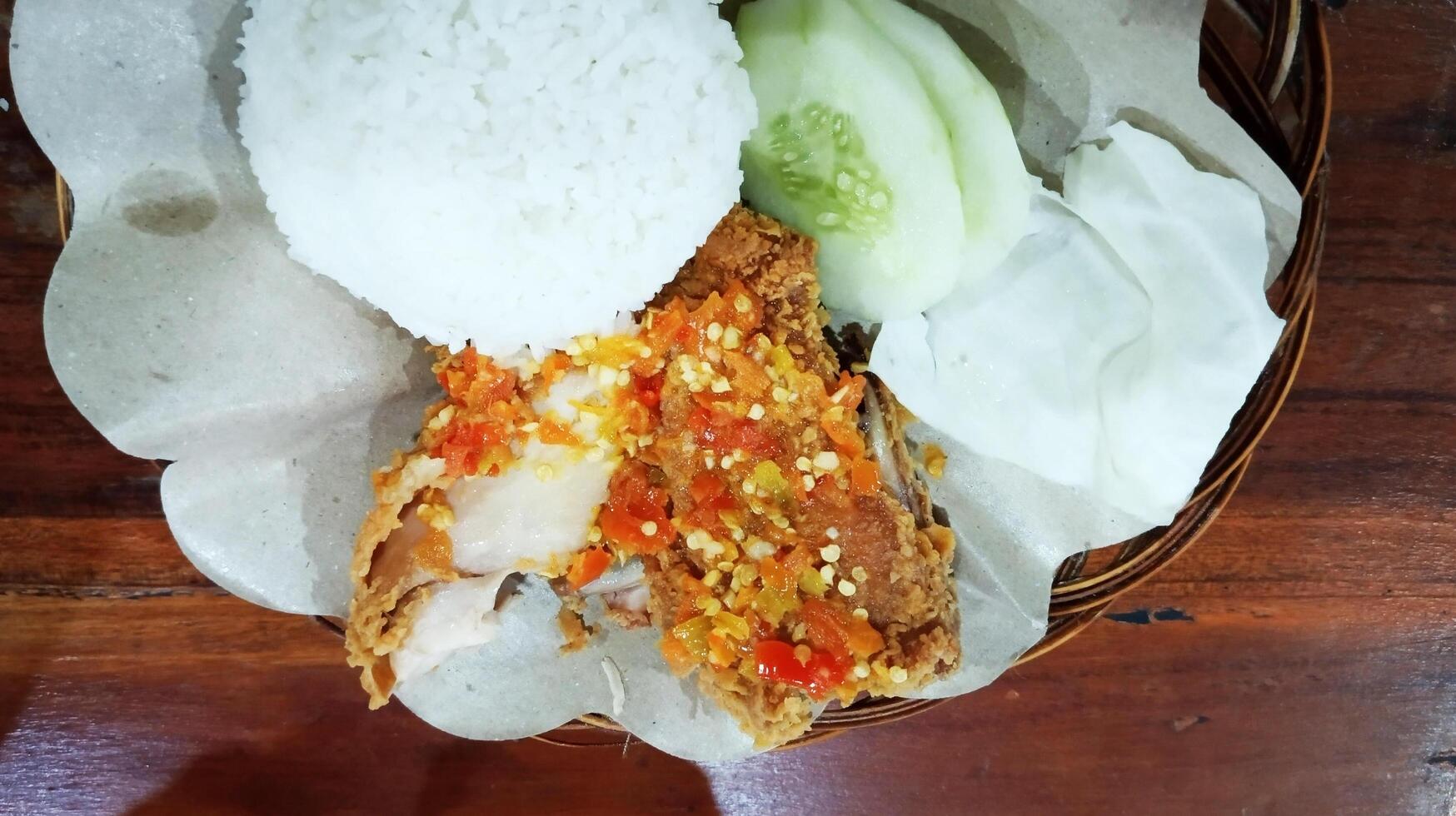 Ayam geprek indonesisch Essen knusprig gebraten Hähnchen mit würzig Chili Soße serviert mit Reis und frisch Gemüse foto