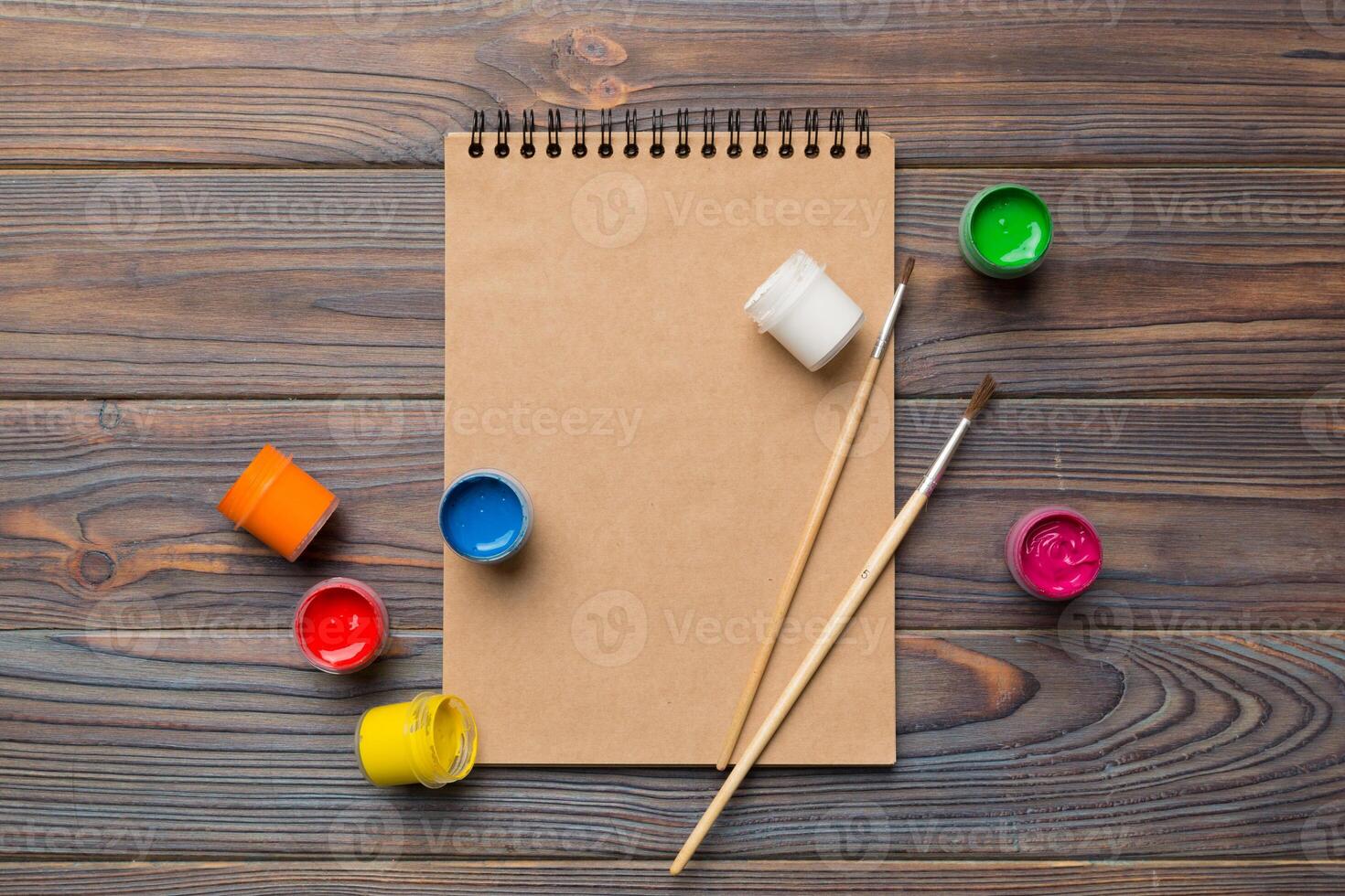 Album Seiten und malt, Bleistifte, Bürste auf ein farbig Hintergrund. oben Aussicht mit leeren Raum. Arbeitsplatz zum Kreativität. Zuhause Lehren Konzept Zeichnung foto