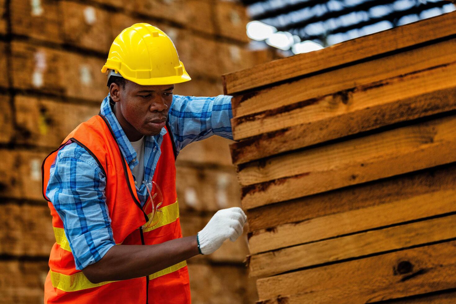 afrikanisch Arbeiter Zimmermann tragen Sicherheit Uniform und schwer Hut Arbeiten und Überprüfung das Qualität von hölzern Produkte beim Werkstatt Herstellung. Mann und Frau Arbeitskräfte Holz im dunkel Warenhaus Industrie. foto