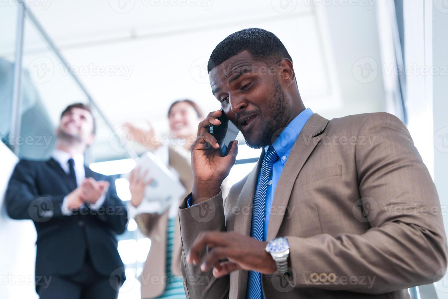 Clever schwarz Geschäftsmann Aufpassen Handy, Mobiltelefon Telefon. kahl Erwachsene Mann tragen formal tragen. nachdenklich Afroamerikaner Geschäftsmann im ein perfekt maßgeschneidert passen Stehen im Treppe im Büro. foto
