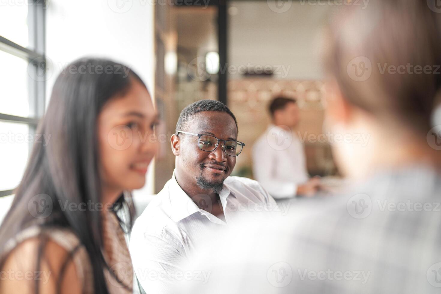 Fokus von Clever afrikanisch Geschäftsmann. vielfältig Angestellte versammelt im Büro haben Spaß Brainstorming während diskutieren Neu Ideen Projekt. gemischtrassig Mitarbeiter Treffen beim Coworking Raum Bereich. foto