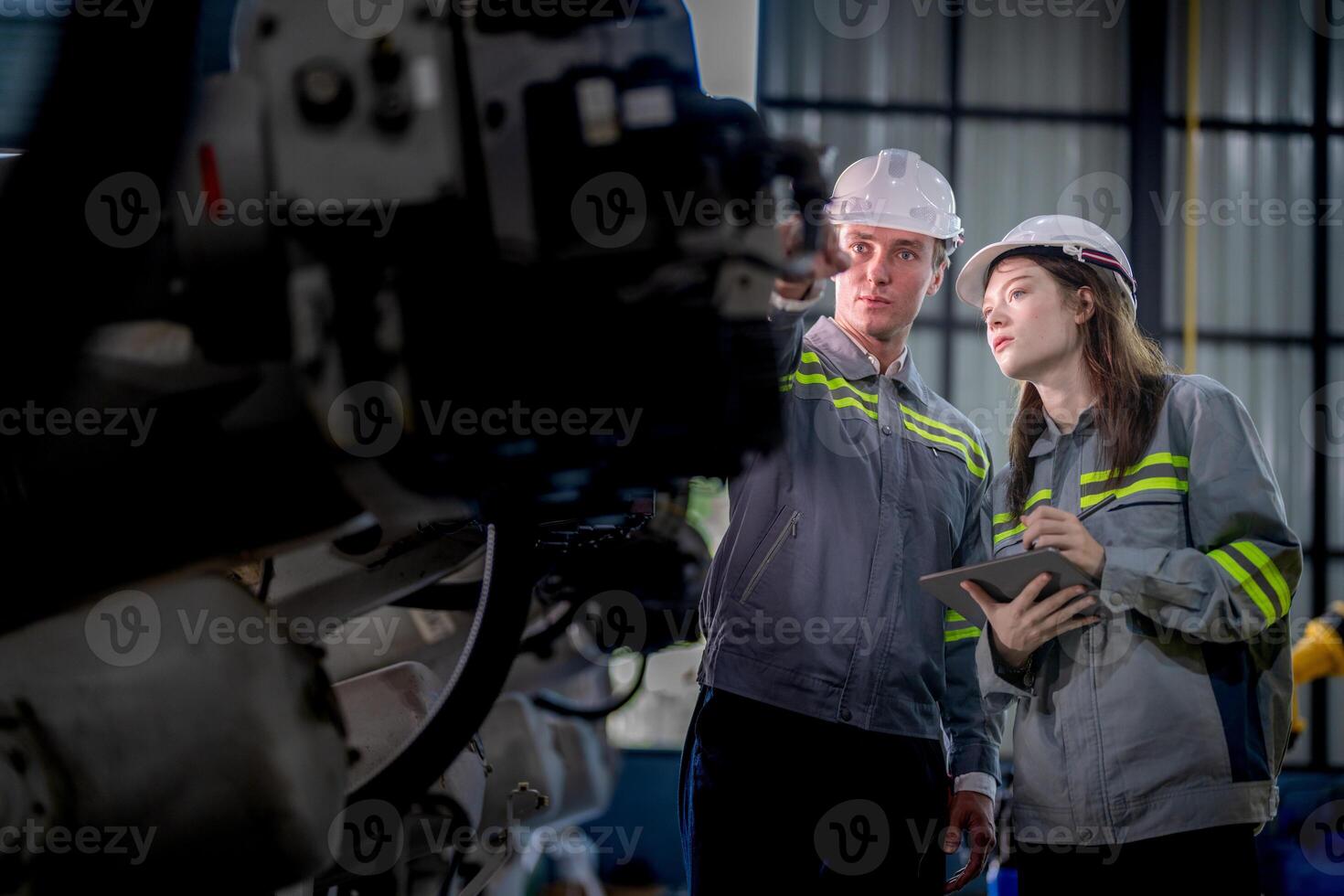 Fabrik Ingenieur Frau inspizieren auf Maschine mit Clever Tablette. Arbeiter funktioniert beim Maschine Roboter Arm. das Schweißen Maschine mit ein Fernbedienung System im ein industriell Fabrik. künstlich Intelligenz Konzept. foto